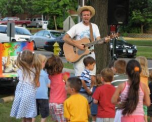 Eric Everett with a group of children outdoors singing Animal Party songs