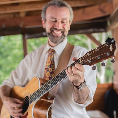 Eric Everett smiling playing guitar in gazebo