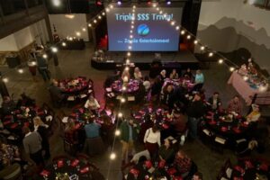 Overhead view of event with dinner tables and Trile Trivia large screen